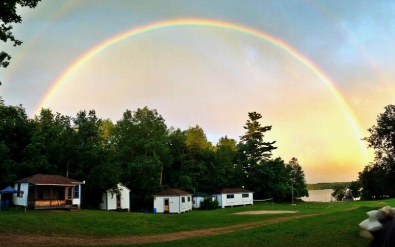cabins on the lake with a rainbow over them