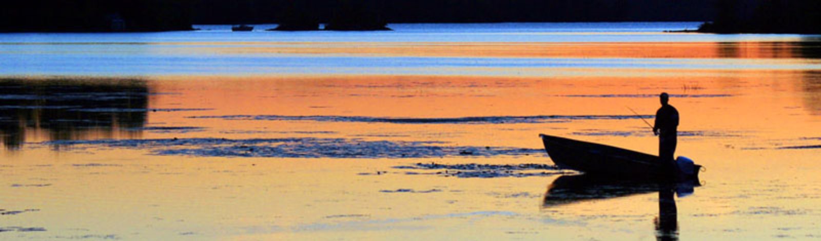 fisherman on lake at sunset