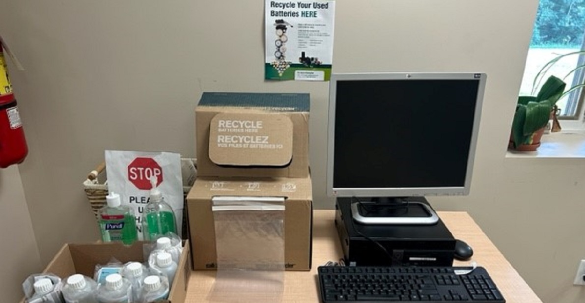 desk with water testing bottles, battery recycling box and computer with keyboard